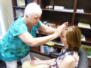 Woman sitting in a chair experiences Therapeutic Touch with a volunteer.